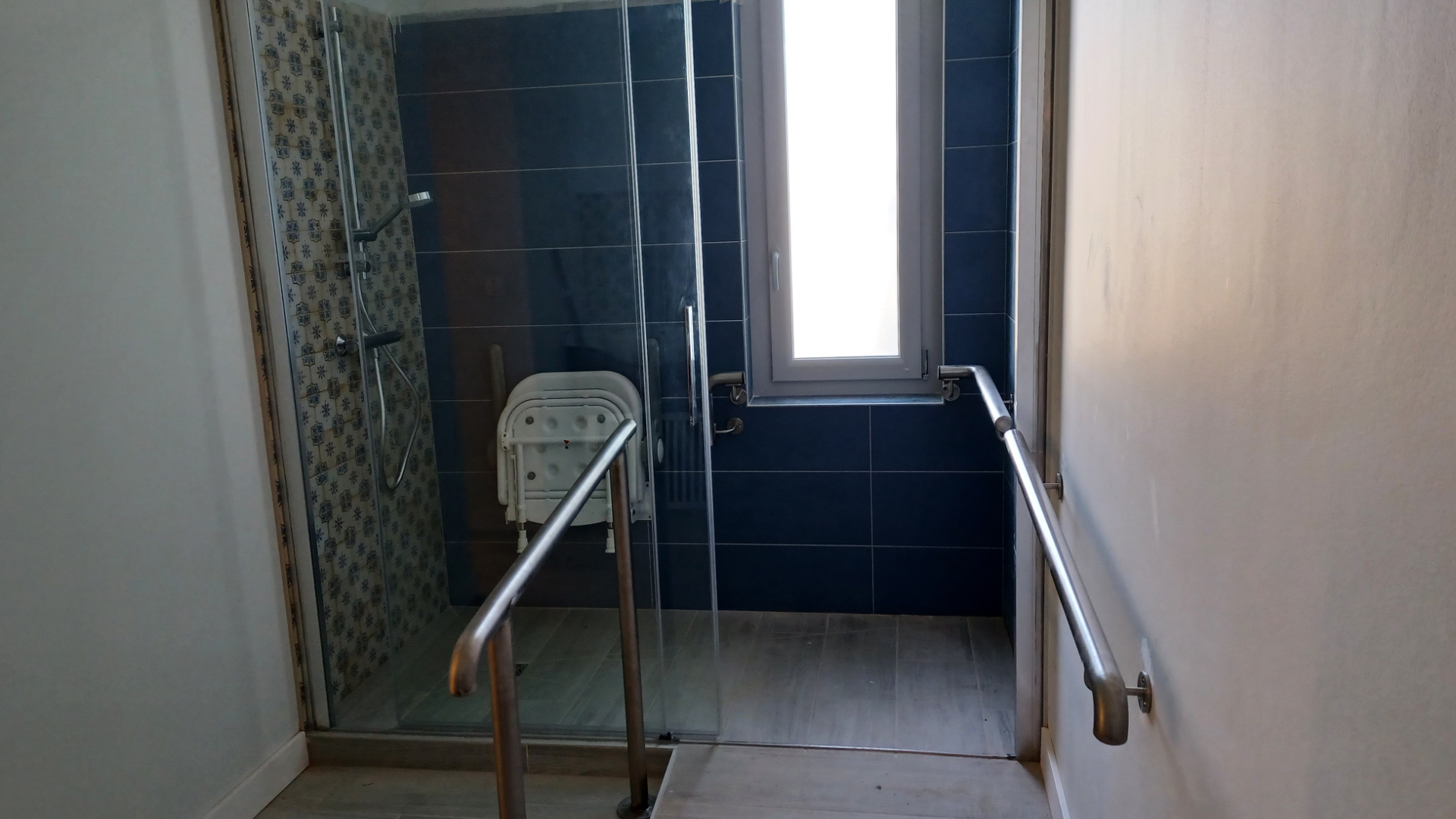 Photo de la salle de bain avec sa rampe pour PMR qui amène à la douche.